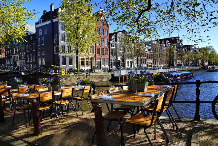 Restauranttische entlang der wunderschönen Grachten von Amsterdam unter blauem Himmel im Frühling - © Jenifoto - stock.adobe.com
